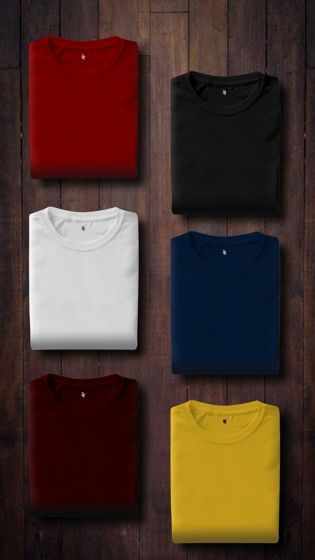 Folded cotton t-shirts in red, black, white, navy, burgundy and yellow on dark wood