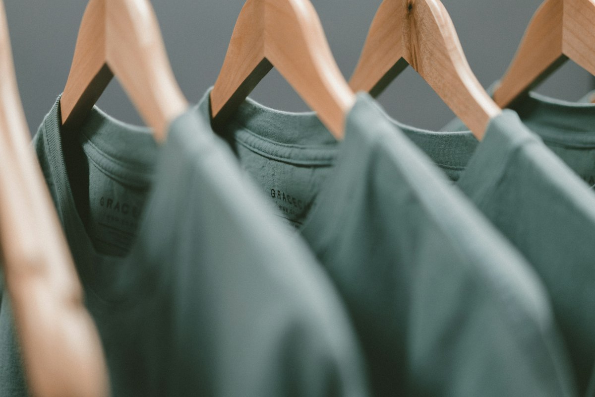Sage-green shirts hanging on wooden hangers