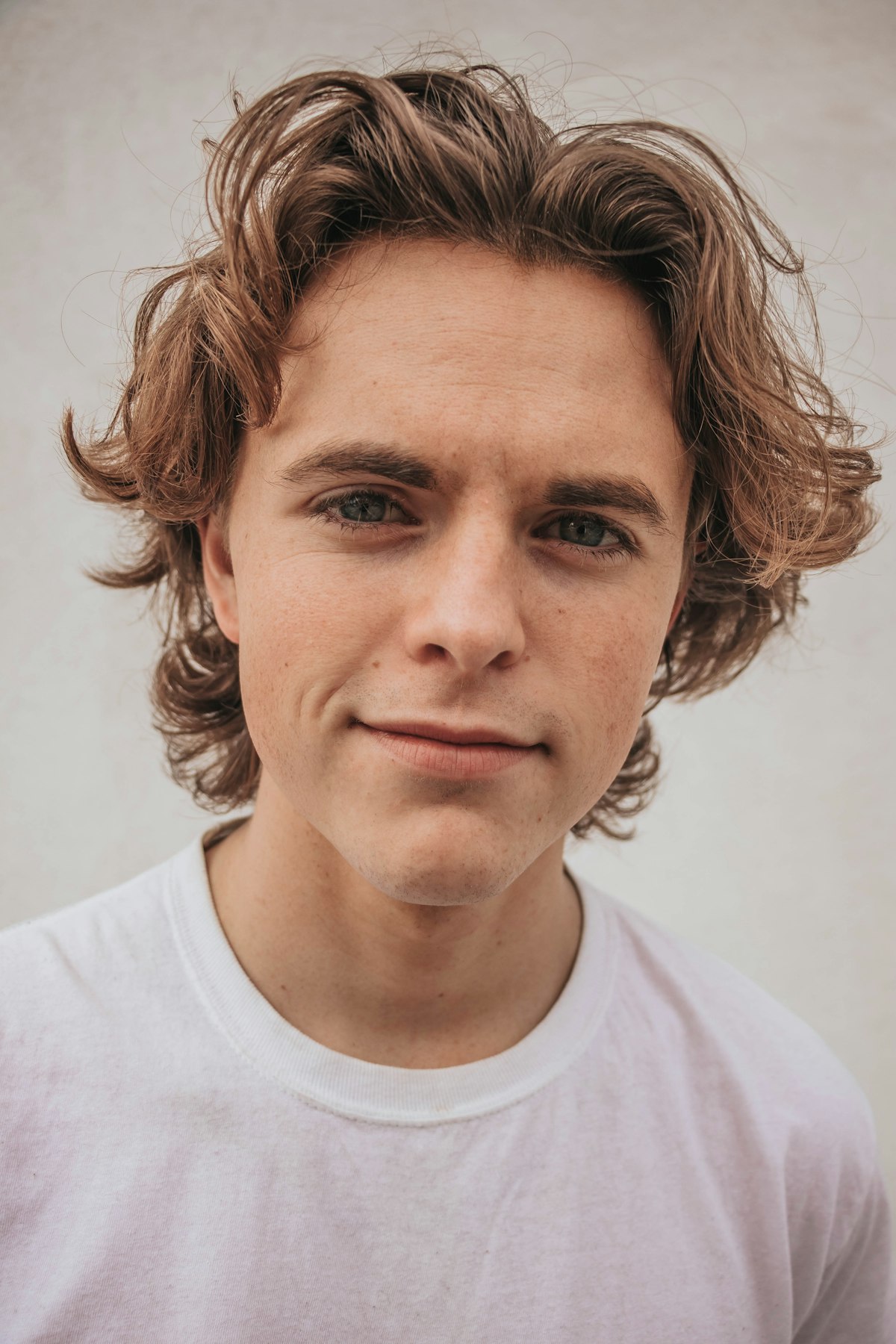 Young man with wavy hair wearing a plain white t-shirt